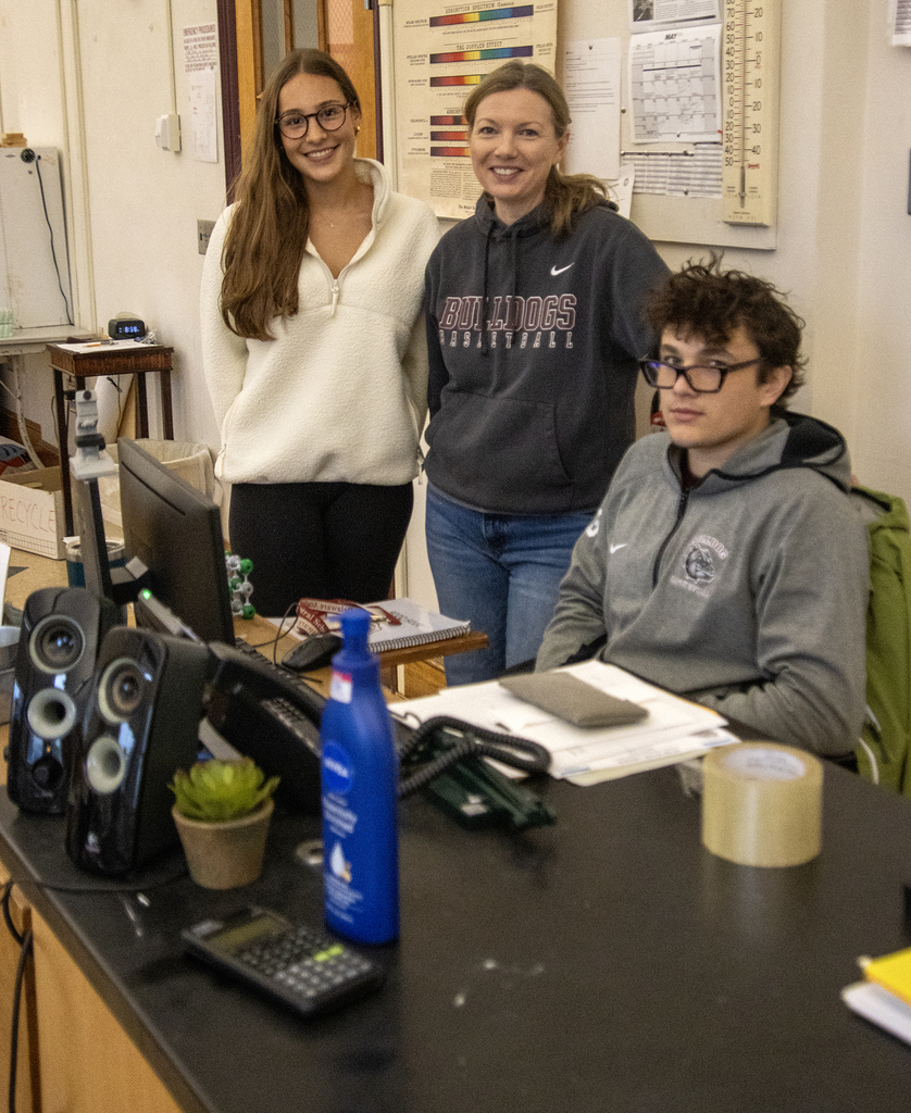 2 students pose with Ms. Morgan in her room