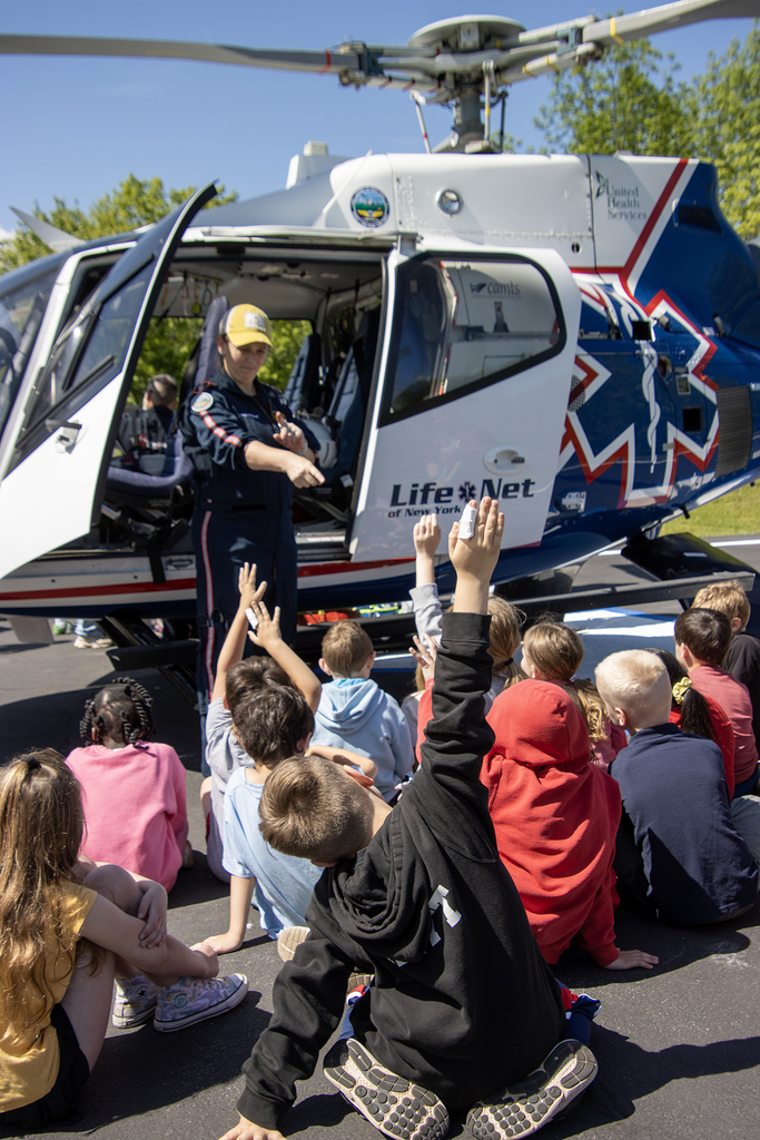 students listen to a flight paramedic as they sit around a helicopter