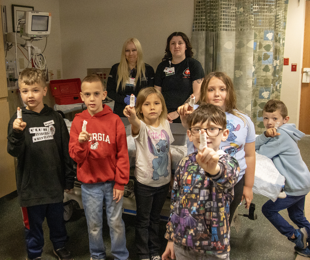 students show off their finger casts; two nurses stand behind them