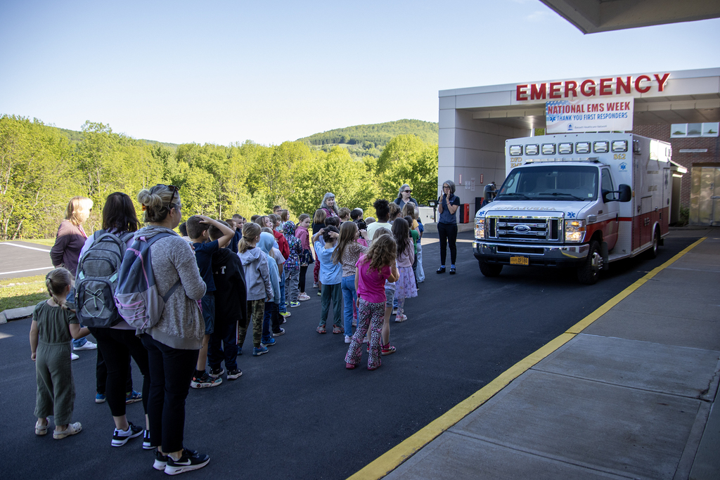 1st grade students listen to a hospital employee seaking outside the emergency room