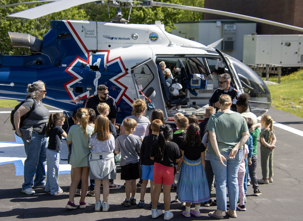 students listen to a flight paramedic and pilot as they stand around a helicopter