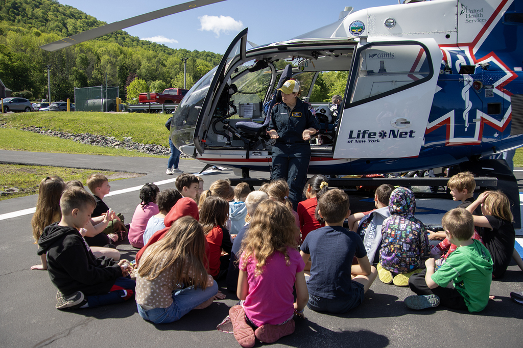 students listen to a flight paramedic as they sit around a helicopter