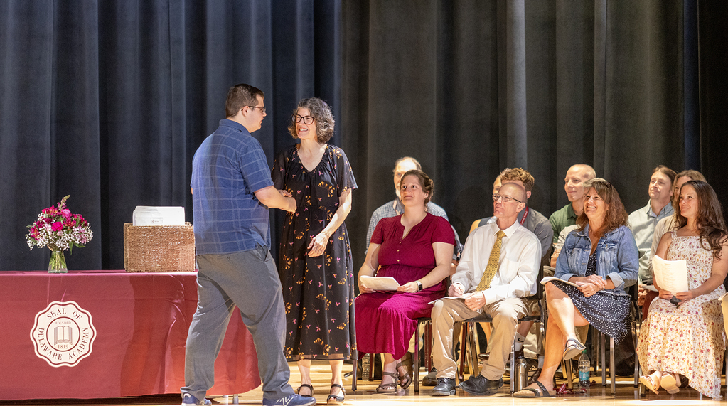 Ms. Trask watches as teacher shakes student's hand