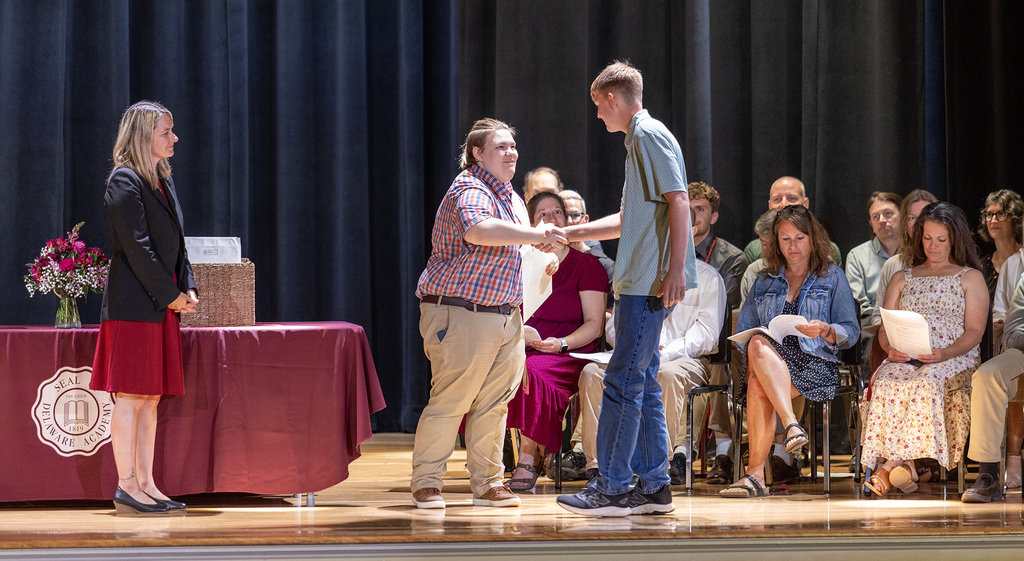 Ms. Trask watches as teacher shakes student's hand