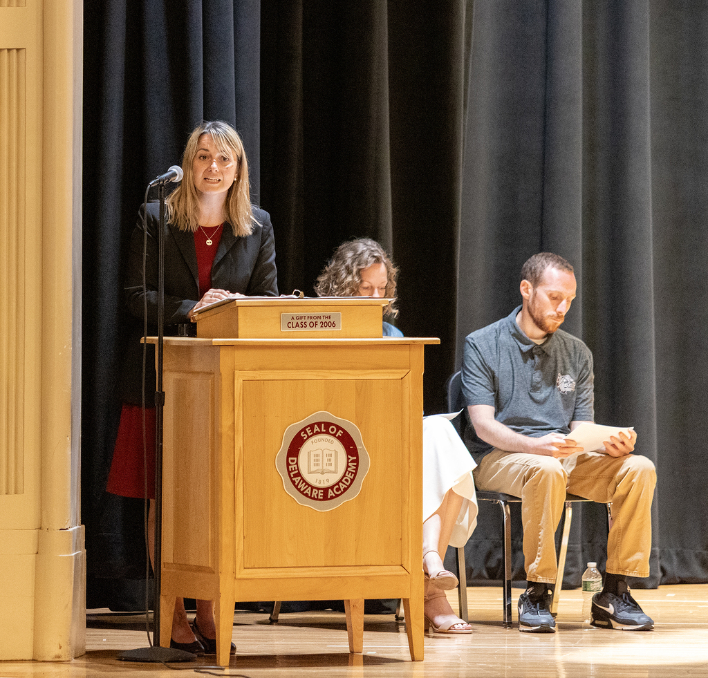 Ms. Trask speaking, Mrs. Kane and Mr. Chase seated behind her.
