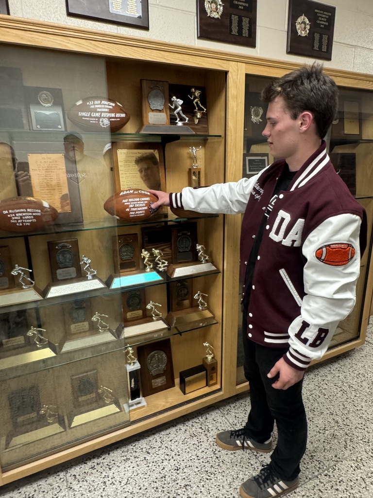 Adam looks at his football in the case