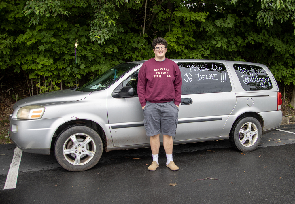 student poses with his decorated van