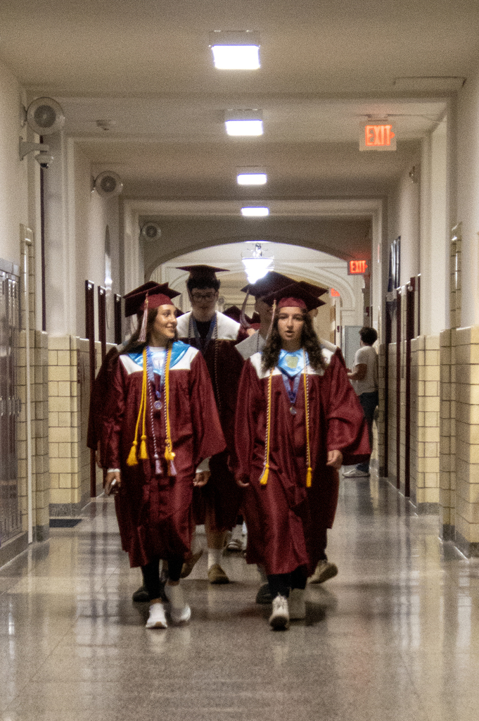seniors in caps and gowns walk through the hallway