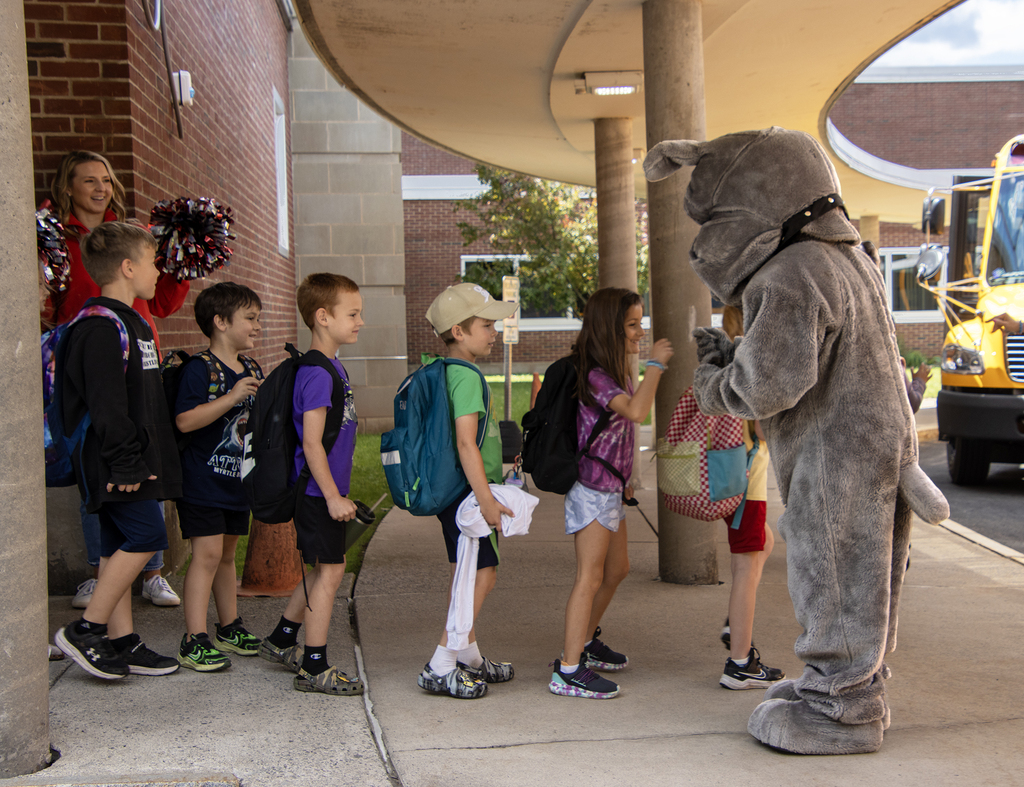 students get high fives from the Bulldog mascot as they leave school
