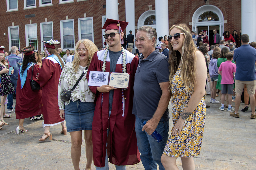 graduate posing with family and his diploma