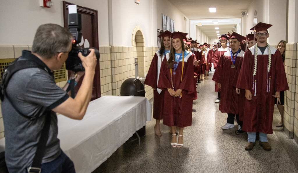 Benjamin Patton taking photos of graduates waiting to process
