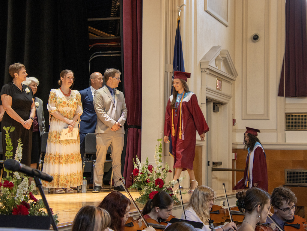 board members on stage watch as the first two seniors mount the stage