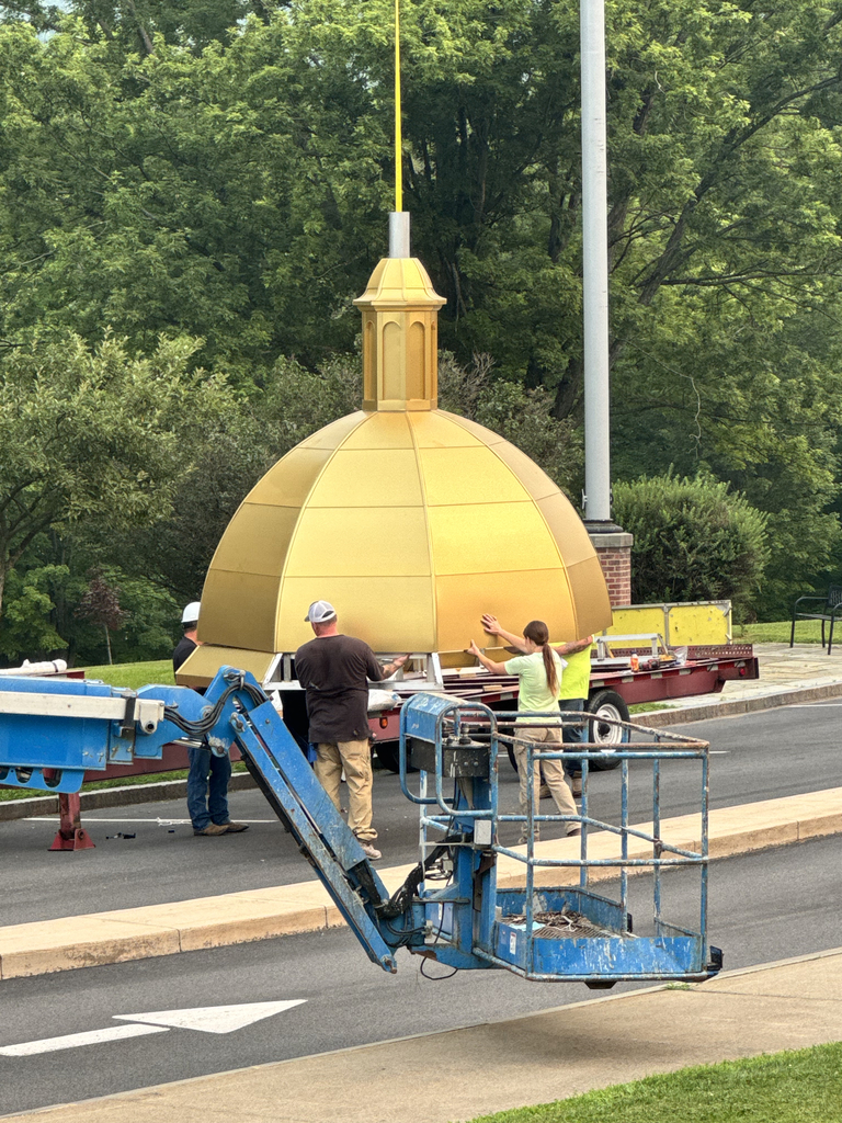 workers on lift work on dome on trailer