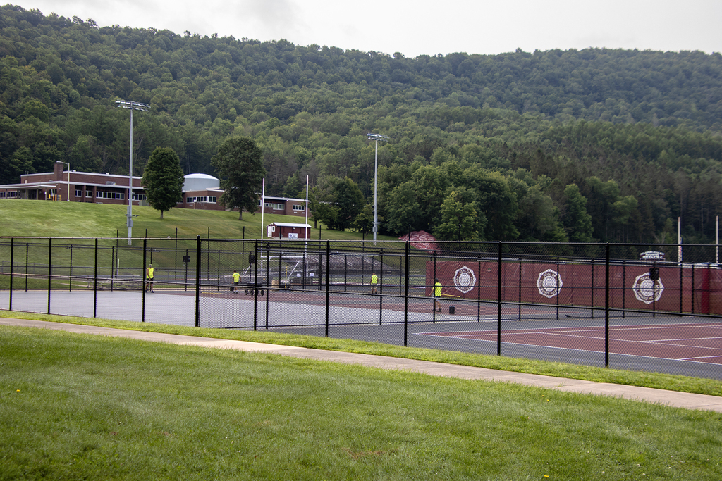 workers sealing the surface on the tennis courts