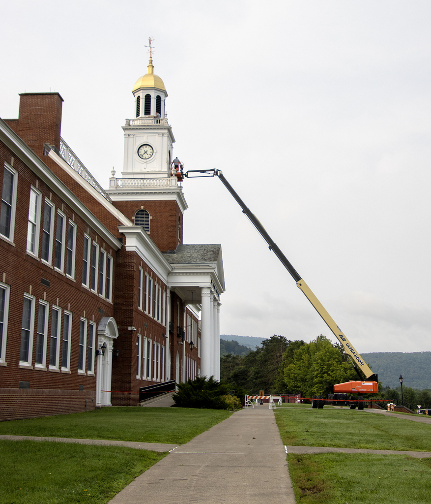 workers in a lift scraping paint on the bell tower