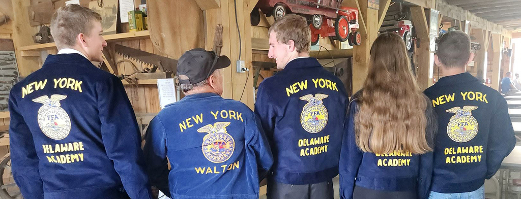Delaware academy tudents and an adult wearing FFA jackets, seen from the back