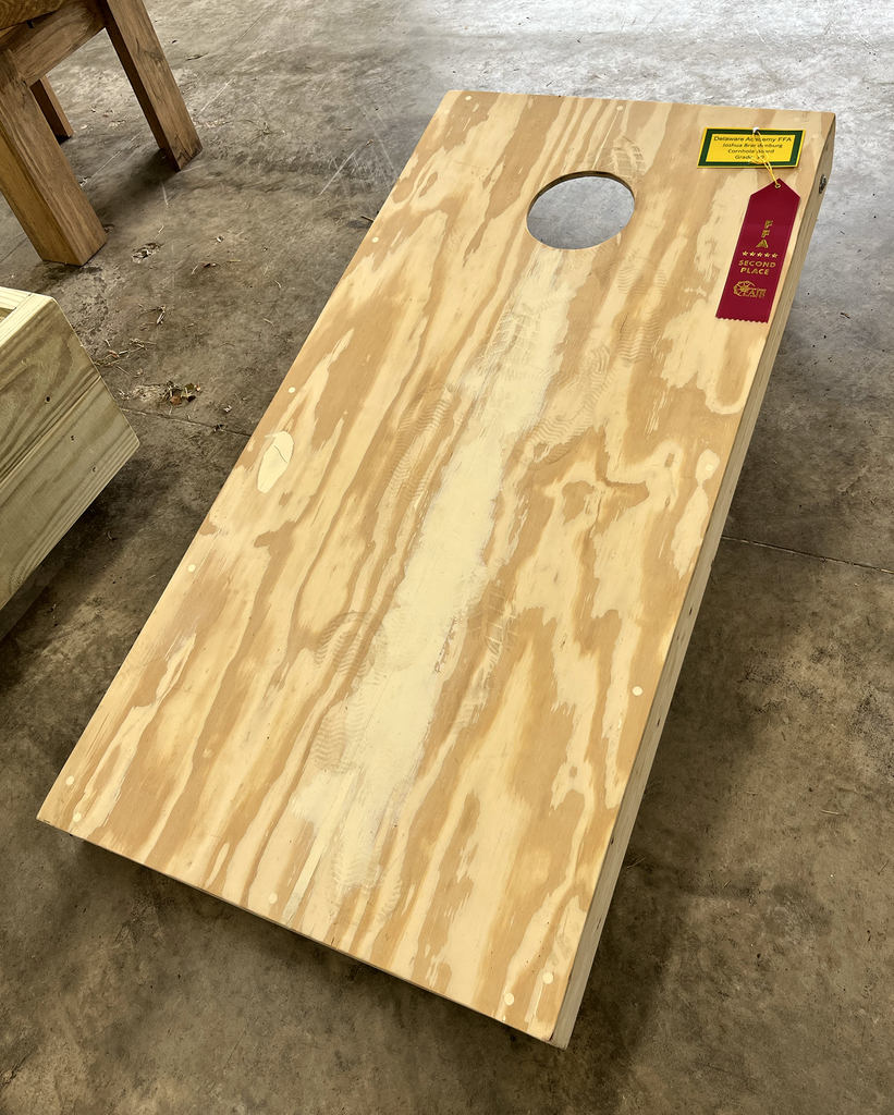 student-made cornhole game with a red ribbon
