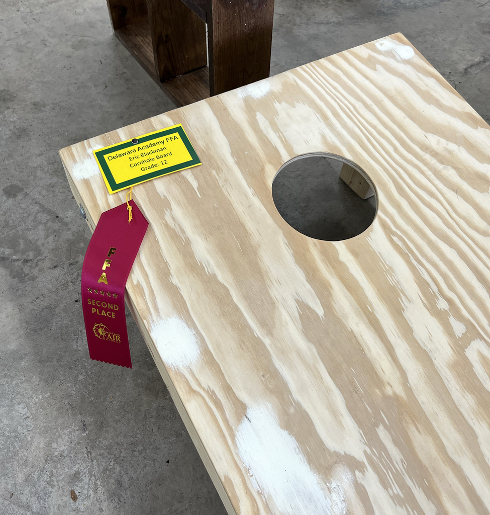 student-made cornhole game with a red ribbon