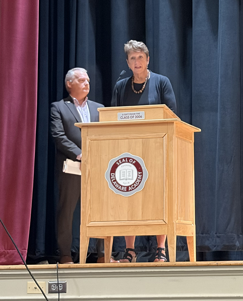  Carey Shultz stands behind Tammy Neumann as she speaks on stage