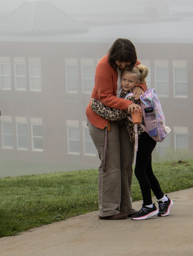 Ms. Oliver hugs an elementary student