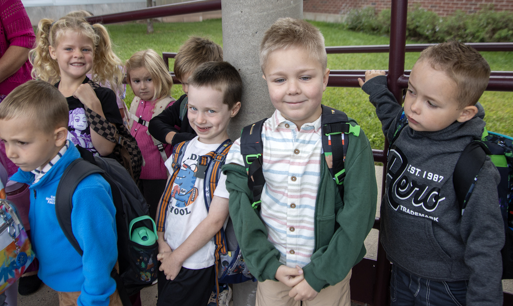kindergarteners smile as they wait to head into school