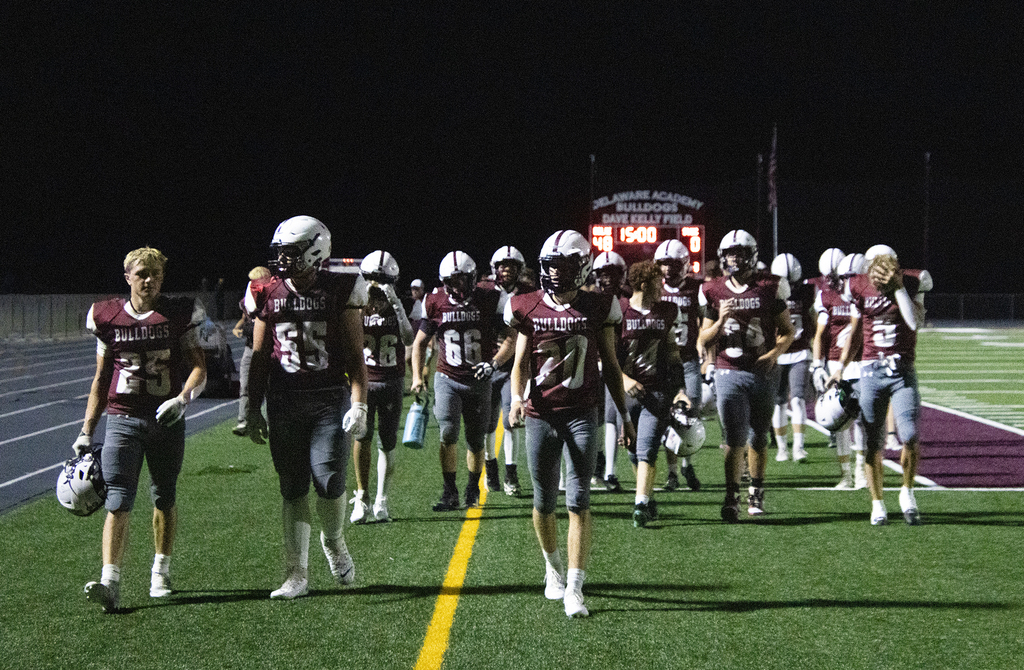 football team leaving field; scoreboard in background shows Delhi 48 SVEC 0.