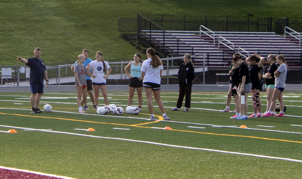 Coach talking to girls soccer players on the field