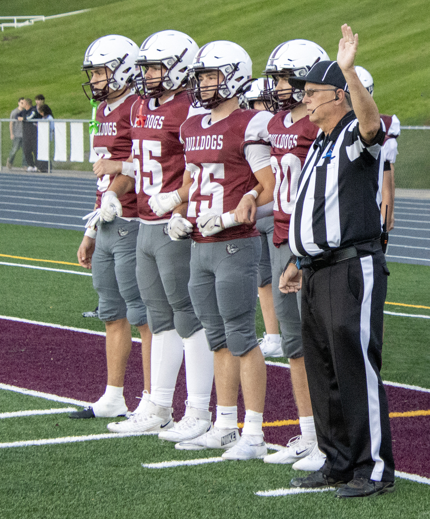 4 football team captains locked arms, standing with the referee