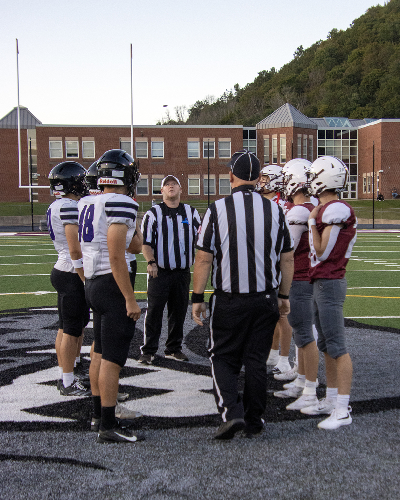 Team captains and two referees watch the coin toss at midfield