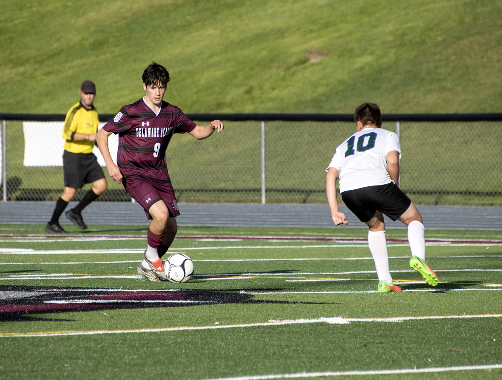 two soccer players and an official in action