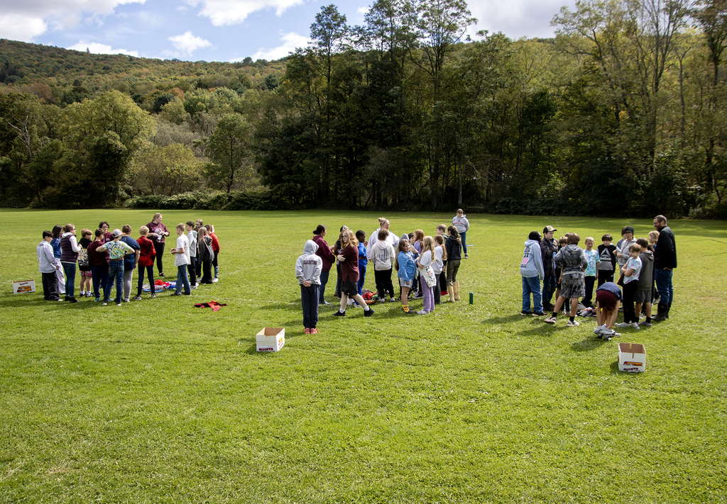 Students and teachers are gathered in 3 groups on the field