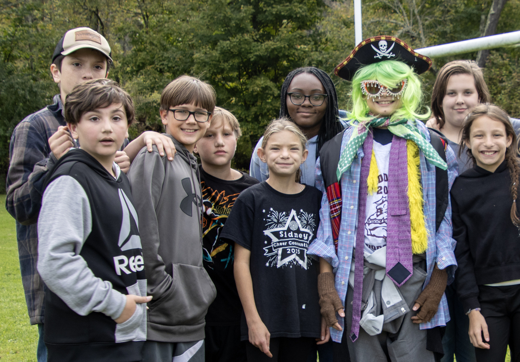 group of students pose for photo with one student dressed in funny costume