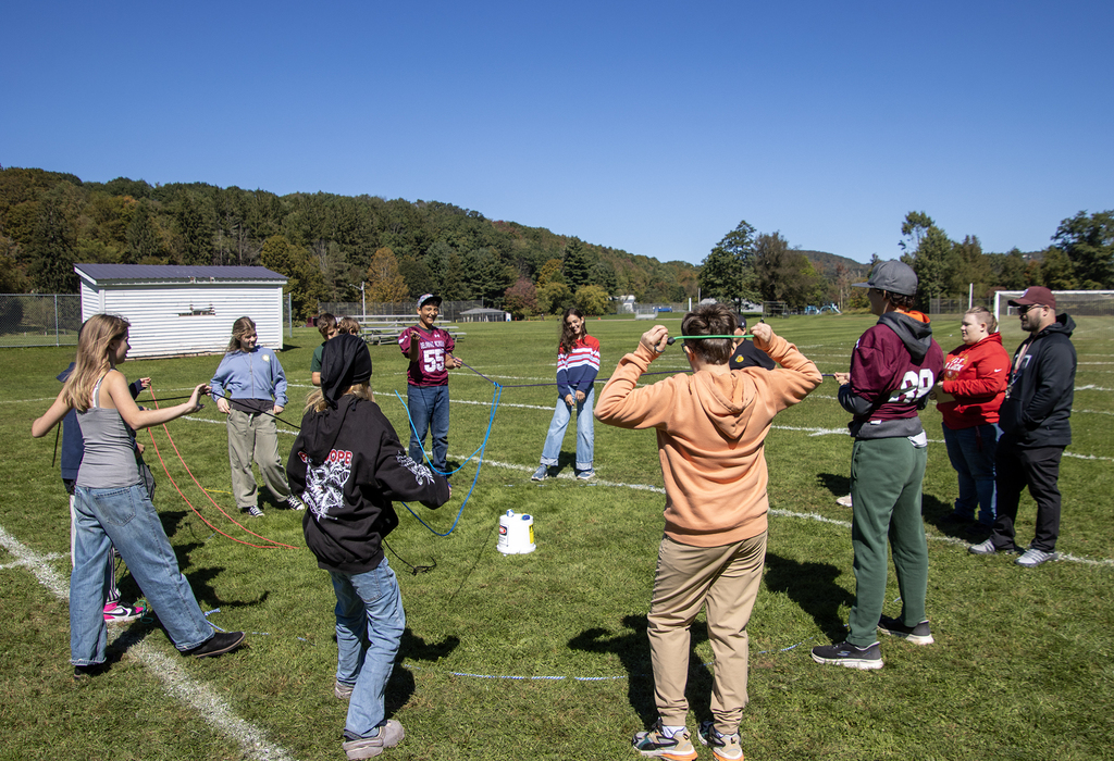 a large group of 7th grade students attempt to move a small ball using connected strings