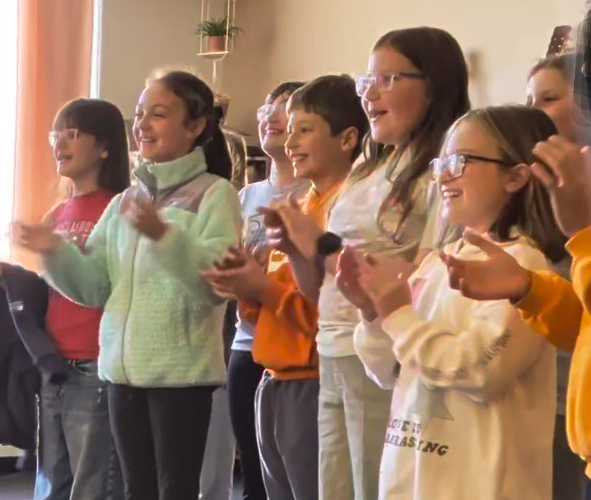 students clapping and performing a song for Mrs. Keene