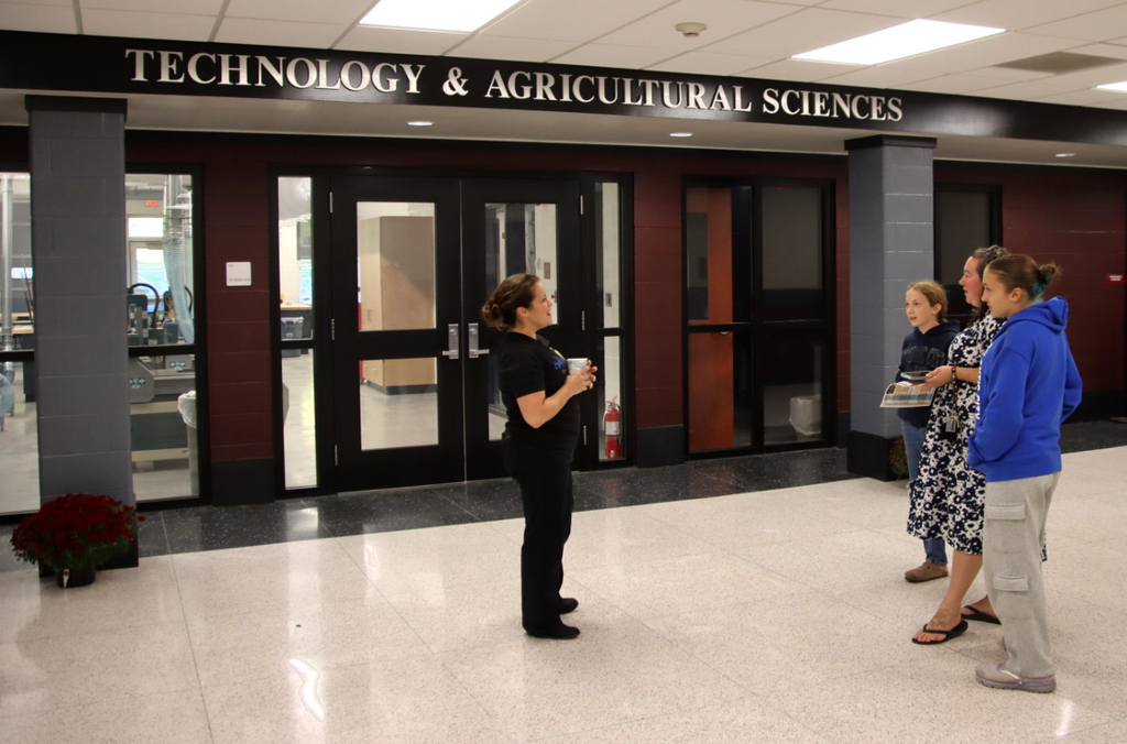 teacher talking to two students and family outside the Technology & Agricultural Sciences lab