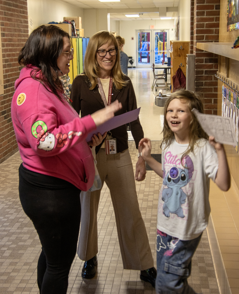 mom talks to special ed teacher while student spmiles for the camera