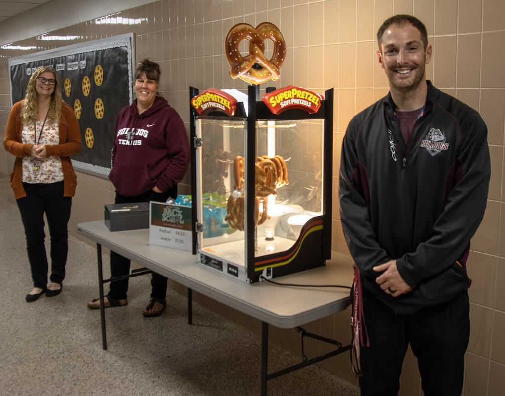 3 safety patrol advisors pose next to pretzel concession