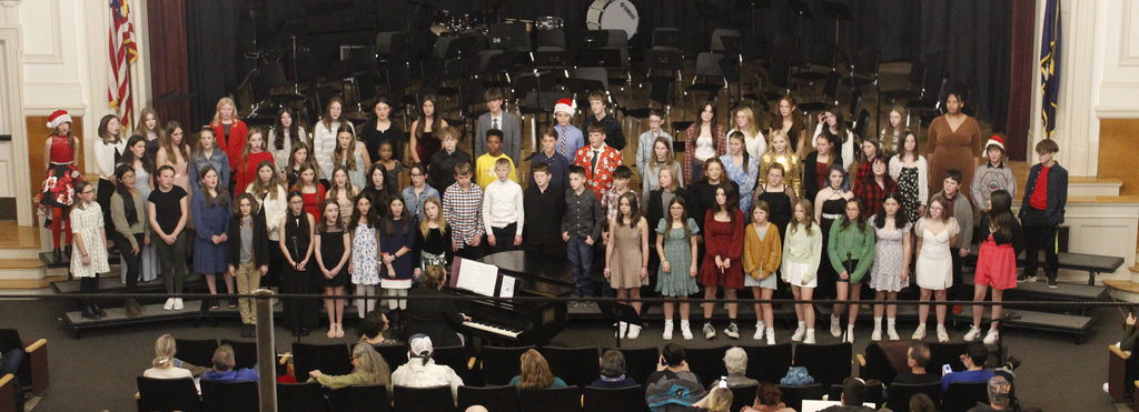 The full chorus on the risers, music teacher is at the piano