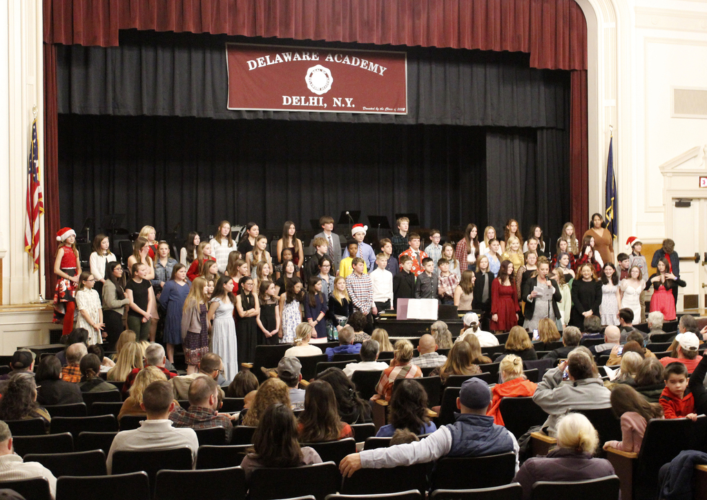 the music teacher at the microphone, with the full chorus on the risers