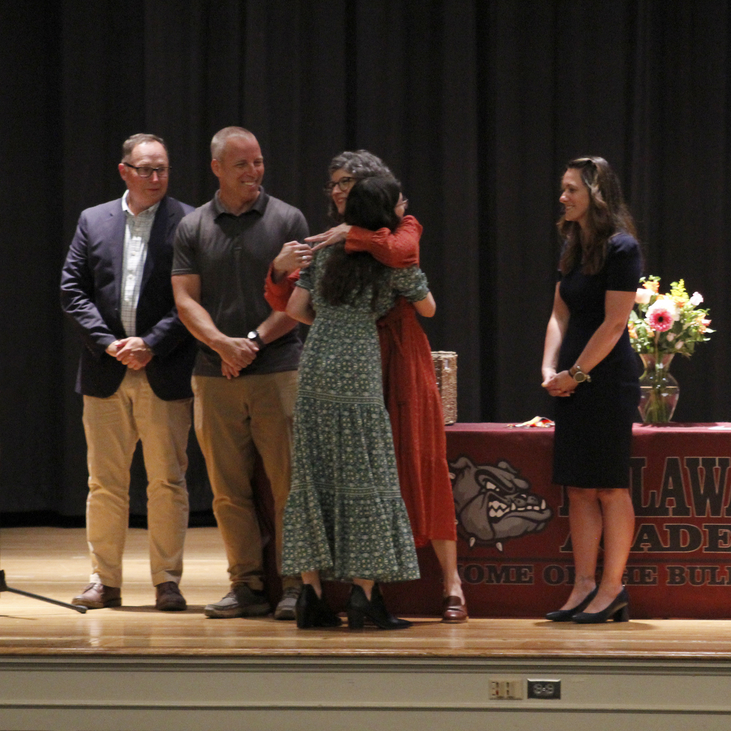 student receiving award, getting hug
