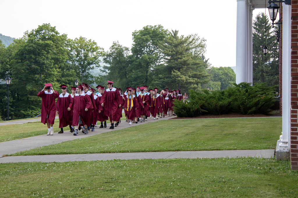 seniors in caps and gowns in front of school