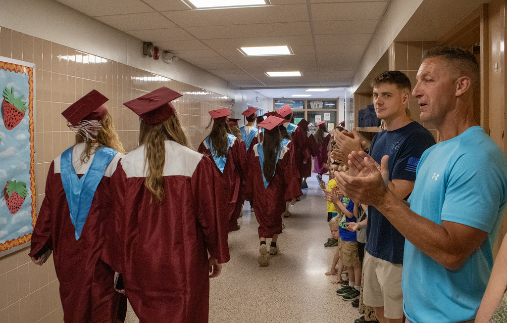 seniors in caps and gowns walk in hallway