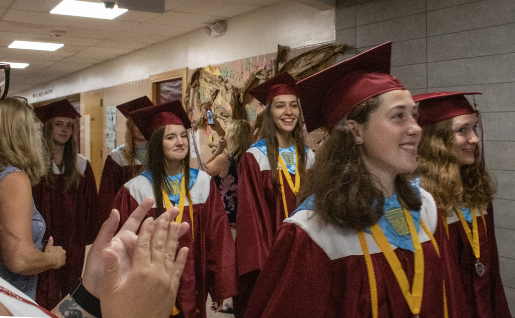 seniors in caps and gowns walk in hallway