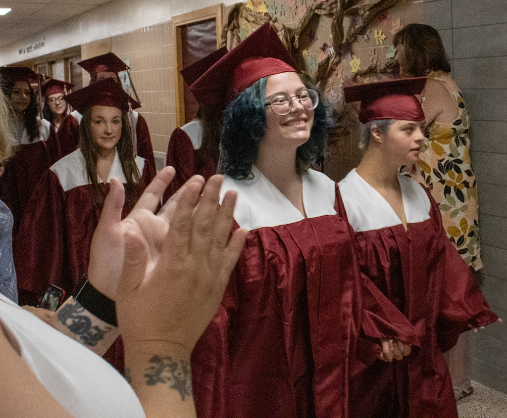 seniors in caps and gowns walk in hallway
