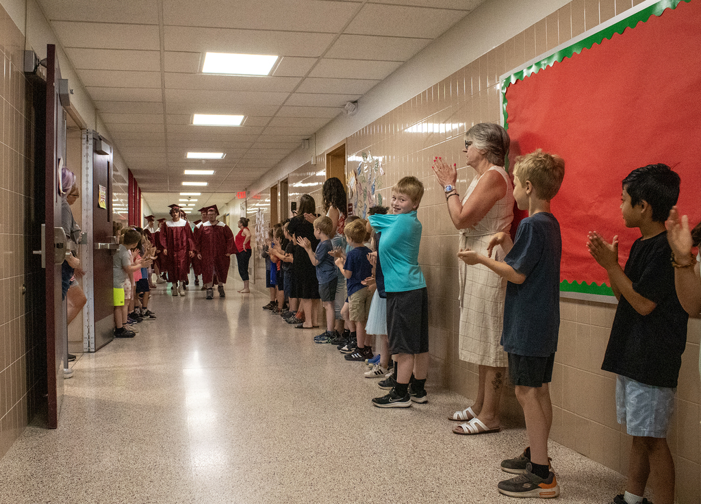 seniors in caps and gowns walk in hallway