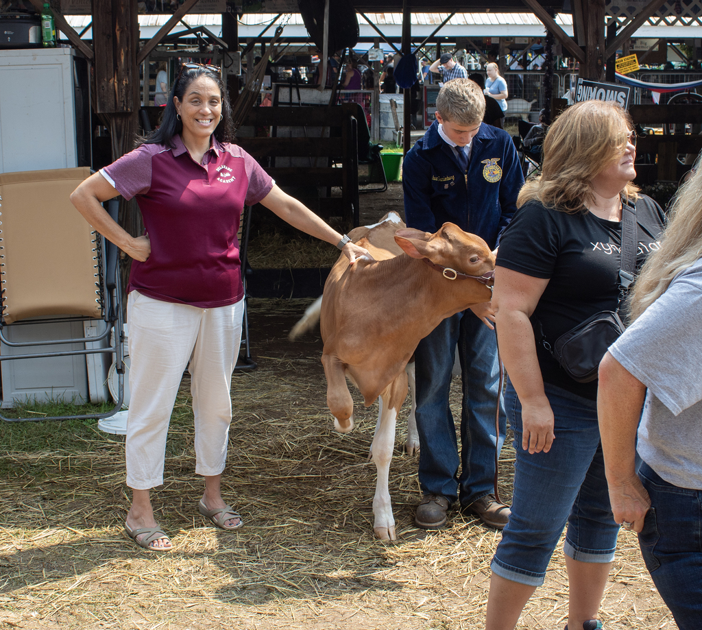prinicipal smiles next to cow