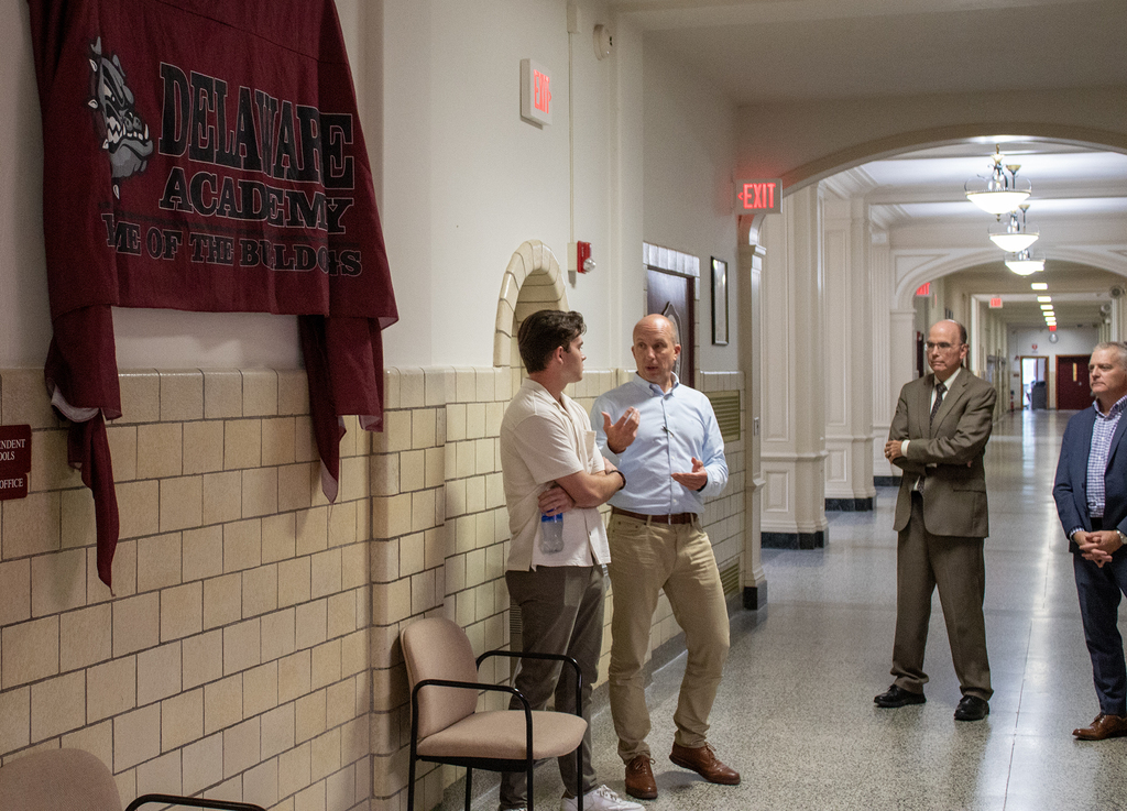 two adults discuss a painting; two other adults watch