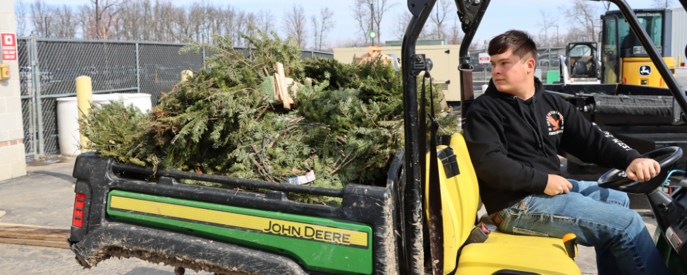 Student driving tractor full of wreaths