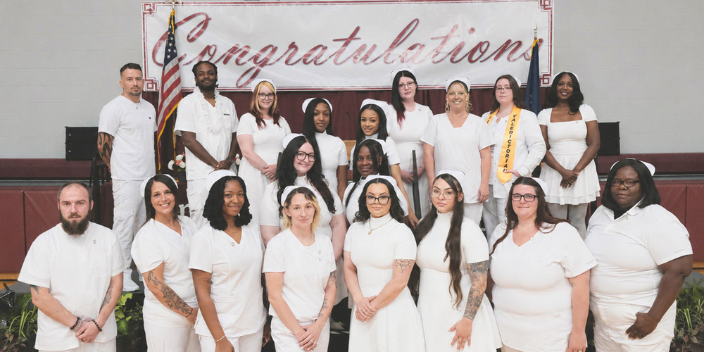 Group photo of LPN graduates, Congratulations banner in the background