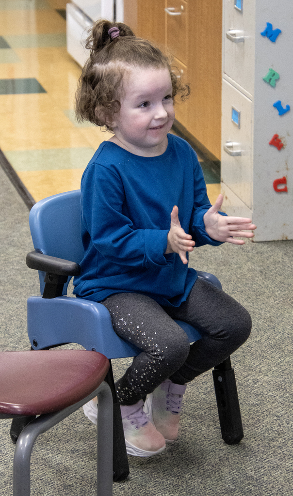 smiling child in a chair claps hands